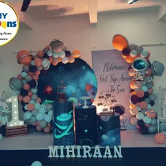 A "First Trip Around the Sun" space-themed birthday. This setup features a galaxy backdrop, astronaut cutouts, and a balloon arch with planet details.