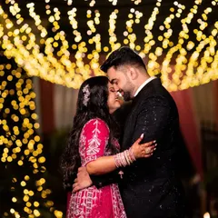 A magical reception photo under a canopy of fairy lights. This romantic shot captures the couple's embrace against a beautiful bokeh background, perfect for a grand finale to the wedding album.