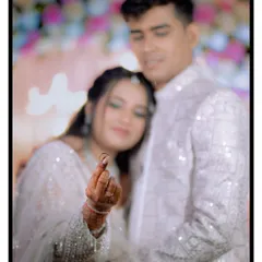 A creative portrait where the bride proudly displays her new ring to the camera. The focus is sharp on the ring, with the happy couple softly blurred in the background.
