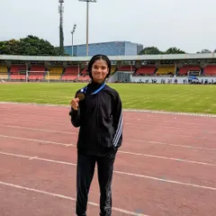 An athlete holding her bronze medal on the track after competing in the 80m hurdles at the junior state meet.