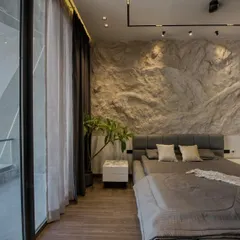 This bedroom showcases an industrial-chic aesthetic with a dramatic, custom-made textured rock wall as the headboard. Floor-to-ceiling windows connect the raw, indoor textures with the view outside.