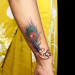 This vibrant peacock feather and Om symbol was designed to cover and correct a previous tattoo. The bright colors and bold lines create a beautiful new focus point.