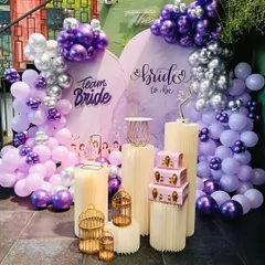 I had so much fun creating this 'Team Bride' setup for a bridal shower. The decor features a custom backdrop with a beautiful balloon arrangement in shades of purple, lilac, and silver. The different-sized pedestals and gold birdcages add a touch of whimsy and are perfect for placing gifts or desserts.