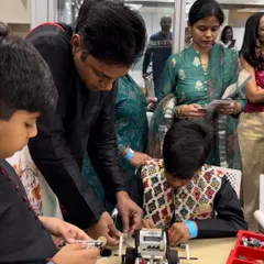 A father provides guidance to his son during a building session. These moments of collaboration are what make our community special, creating a supportive environment for our young engineers to thrive.