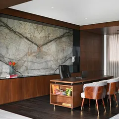 For this Chairman's office, we aimed for quiet luxury. The centerpiece is a book-matched marble slab that acts as a piece of art, complemented by rich wood paneling and a bespoke desk, creating a space that is both powerful and serene.