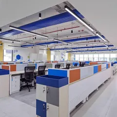 This bright and clean open-plan office uses brand colors to create a cohesive and energetic environment. The layout is designed for efficient movement and clear sightlines, with low partitions on workstations to facilitate team communication.