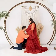 A stylish maternity session in my Jaipur studio, featuring a popular boho theme with natural textures and soft lighting. The father-to-be kisses the baby bump, creating a tender moment.