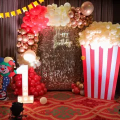 Step right up to the greatest first birthday! This carnival-themed party was a blast to create, featuring a massive popcorn box prop made of balloons, a golden sequin backdrop, and a light-up marquee number '1'.