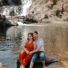 A serene portrait of a couple sitting by a waterfall in Udaipur. The natural setting provides a beautiful and tranquil backdrop for this romantic moment.