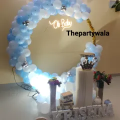 A simple and elegant baby shower ring decoration in light blue and white, with an 'Oh Baby' neon sign.