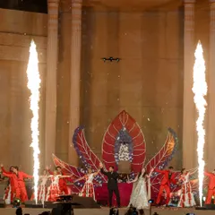A high-energy performance on the 50-foot high grand stage, complete with pyrotechnics. The stage itself features a floral-like unfolding backdrop, adding a dynamic element to the entertainment.