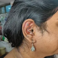 A beautifully healed ear project featuring a flat piercing with a flower top and a daith piercing with a crescent moon ring. We help you choose jewelry that complements your style.
