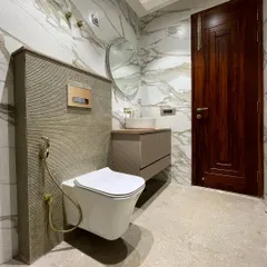 We used a combination of textures and tones in this bathroom. The walls are clad in a beautiful marble-look tile, while the area behind the toilet features a grooved stone tile. Brushed gold fixtures add a final touch of luxury.
