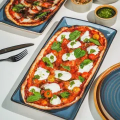 A top-down shot of a rectangular Margherita pizza with fresh burrata, styled with hard light and sharp shadows. This clean, graphic approach is modern and perfect for a digital menu.