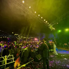 A wide shot from the stage, looking out at a massive wedding crowd. The combination of stage lighting, smoke effects, and a high-energy audience creates a truly epic party atmosphere.