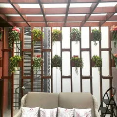 My work goes beyond standard green walls. Here, I designed a custom wooden slat partition with integrated hanging planters to create a stylish and green separation for a cozy seating area.