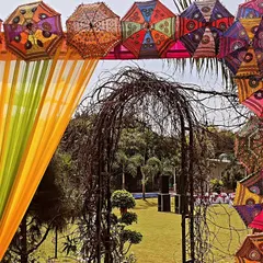 A unique entrance arch for a Holi event, constructed with colorful fabrics and decorated with traditional embroidered umbrellas. This design combines festive colors with artisanal Indian elements.