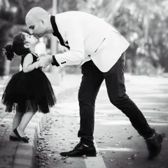 A father's gentle kiss for his little girl. This candid black and white street shot is timeless, capturing a fleeting moment of pure love and connection between a dad and his daughter.