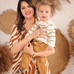 A beautiful portrait of a mother holding her curious baby boy. Both are looking towards the camera, creating a classic shot within our modern, boho-inspired studio setup.