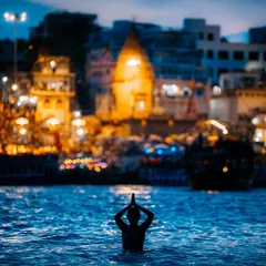 This is the same powerful moment of devotion in Varanasi, captured from a slightly different angle. The deep blue of the water contrasts with the warm, illuminated city, creating a spiritually charged image.