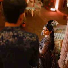A beautiful over-the-shoulder shot during an evening function, capturing an intimate glance between the couple amidst the celebration.