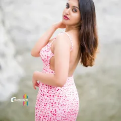 A modern outdoor portrait featuring a pink backless dress. The natural, rocky background provides a great texture contrast to the soft dress.