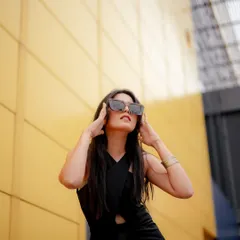 A low-angle shot against a bright yellow wall creates a bold, graphic look. This composition makes the model in the black dress appear powerful and is perfect for an eye-catching ad campaign.