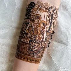 A close-up of the finished Radha-Krishna portrait on the arm, showing the fine details in their expressions and attire.