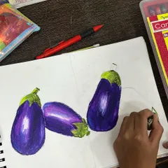 Using oil pastels to draw brinjals, this student is learning about blending colors to create smooth gradients and highlights. This is a great exercise for improving observation and concentration.