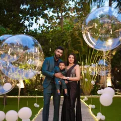 A stylish family poses for a photo at a jungle-safari-themed first birthday party. The balloon decor and lush green surroundings create a perfect backdrop for memorable pictures.