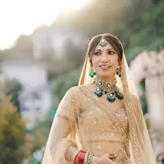 A beautiful, sun-kissed portrait of the bride, with the soft light highlighting her features and the stunning green and gold jewelry she wears.