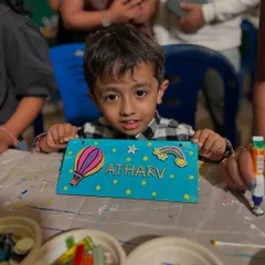 A little boy showing off the colorful nameplate he painted at our stall. The hot air balloon is a great touch.