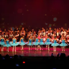 Our youngest ballerinas take the stage. This photo captures the magical moment our pre-ballet and kids' ballet students perform at the annual recital, a proud moment for them and their parents.