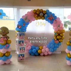 A gender reveal or baby shower setup with a pink and blue circular balloon arch, butterfly accents, and "BABY" blocks.