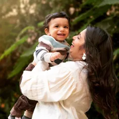A mother celebrating her son's first birthday is also celebrating her own journey into motherhood. The joy in her eyes as she lifts him up is a beautiful testament to this special milestone.