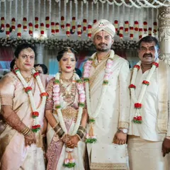 The bride and groom with their parents. Notice how the parents' outfits in shades of cream and light pink subtly coordinate with the main couple's attire.
