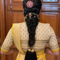 A close-up of a traditional fishtail braid, adorned with a beautiful accessory and finished with a parandi. This is a classic South Indian bridal hairstyle.