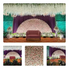 This reception stage features a stunning semi-circular backdrop made entirely of pink and white roses, framed by a green wall and a ceiling of hanging white flowers.