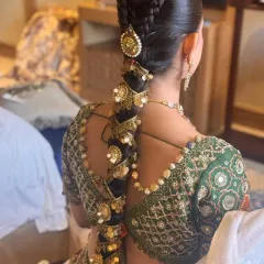 A detailed shot of a heavily accessorized bridal braid, featuring multiple layers of traditional gold ornaments. This style is ideal for a grand, royal wedding look.