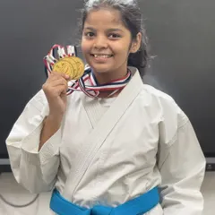 A proud smile from one of our young champions, showcasing her medals. Her success is a reflection of her commitment to consistent training.