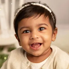 The bright, happy smile of a one-year-old. This close-up portrait beautifully captures the innocent joy and sparkling eyes of a child celebrating her first year.