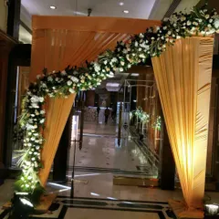A simple yet elegant entrance arch for a hotel wedding. I used a beautiful orange drape and a semi-arch of fresh white flowers to create a warm and inviting entryway for the guests.