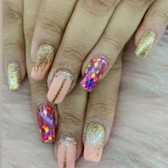A fun, "party on your nails" look. This set combines a peachy nude base with gold glitter, gold-lined accents, and a stunning, iridescent shattered glass effect on the accent nails.