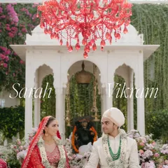 A beautiful portrait of Sarah and Vikram seated at their wedding ceremony. The custom red chandelier contrasts beautifully with the white marble temple structure and lush greenery of the Taj Lake Palace.
