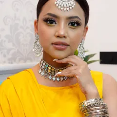 A perfect Haldi look. We created a bright and sunny style with a pop of yellow on the inner corner of the eyes, glossy lips, and sleek hair to go with her yellow outfit and silver jewelry.