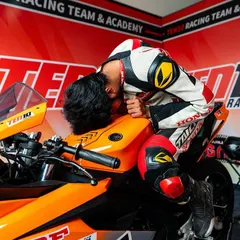 The moments before a race are about pure focus. Here, a rider connects with his machine in the pit garage, mentally preparing for the challenge ahead. This is part of the athletic discipline we instill.