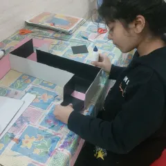 A student carefully assembling her periscope. I guide her through the process, but she does the work herself, learning about angles, reflection, and construction as she goes.