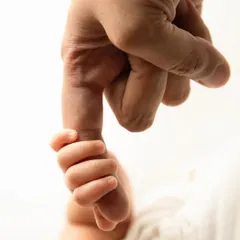 A close up shot capturing a newborn's tiny hand wrapped securely around their parent's finger. This image symbolizes the powerful, instant bond and the start of a lifelong journey together.