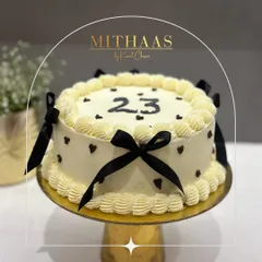 A classic and elegant 23rd birthday cake. The white frosting is decorated with delicate black ribbon bows and tiny black hearts, creating a chic and timeless look.
