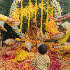 A groom covered in Haldi and flowers, a classic shot that signifies the peak of the celebration. The joy and chaos are palpable.
